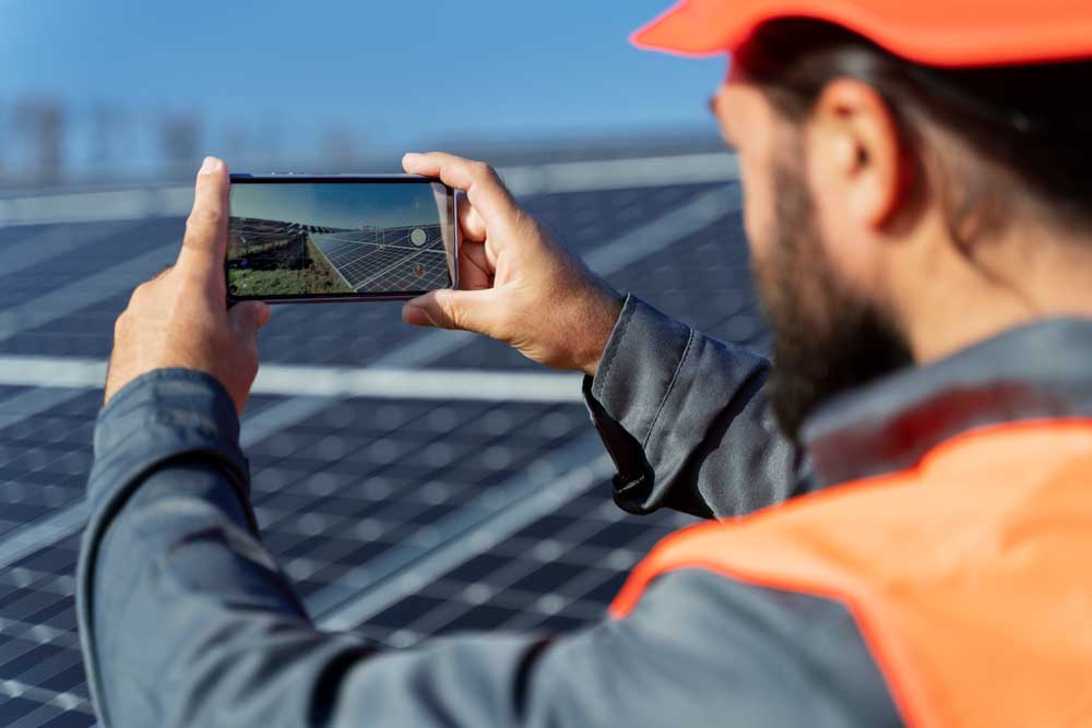 A inspector using tablet to check on solar panels on the roof